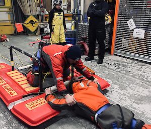 A team member practices using a sea ice rescue pontoon on land pulling 'patient' into safety