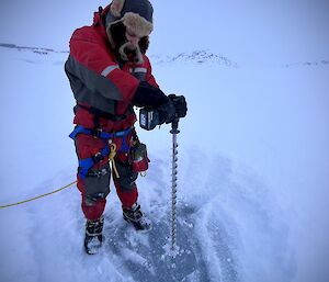 expeditioner Andy drilling sea ice using a one meter drill piece