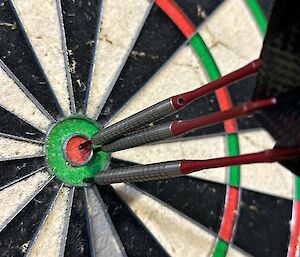 Close up of dart board with three darts in the bulls eye area