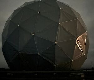 Close up of Satellite Dome which is shining dark grey with grey skies around