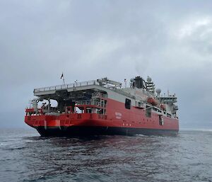 View of RSV Nuyina from the aft end, on a calm, grey ocean