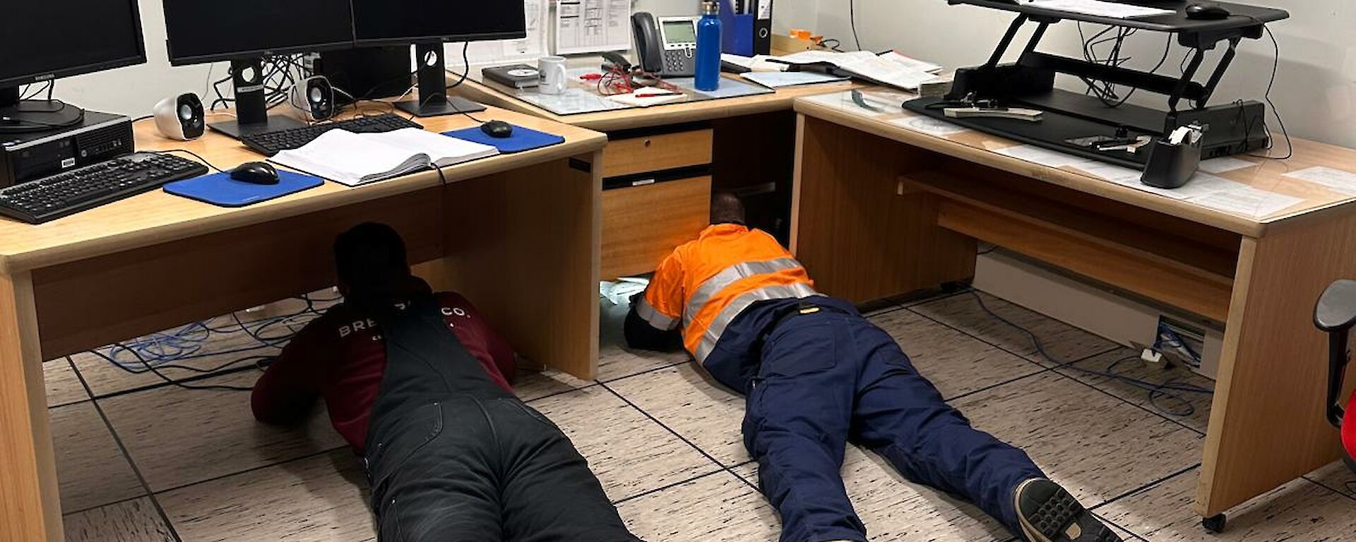 Two expeditioners on the floor trying to fix something electrical