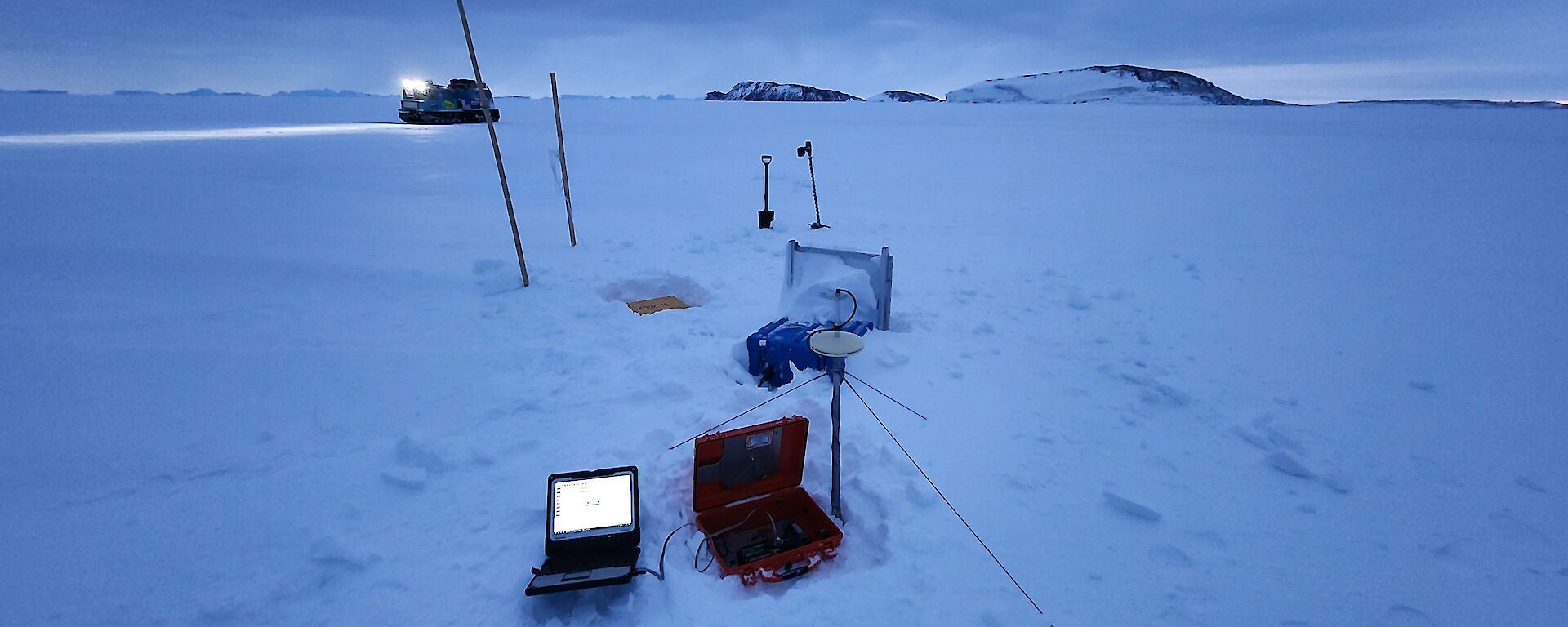 A laptop and electronics equipment sit on a snowy landscape