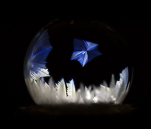 Frosty patterns on a soap bubble light from behind with a torch