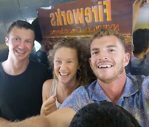 Two young men and a woman taking a selfie and smiling