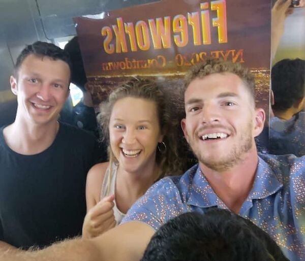 Two young men and a woman taking a selfie and smiling