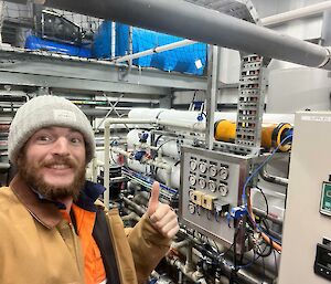 A man wearing a beanie standing in front of electrical equipment