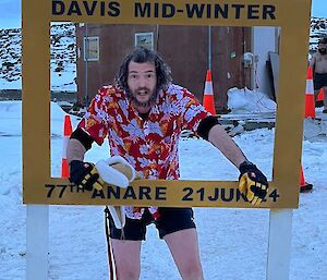 A man in a bright shirt stands inside a photo frame saying 'Davis Midwinter'