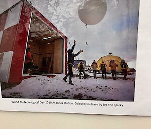A photo on a wall of a person in black releasing a weather balloon