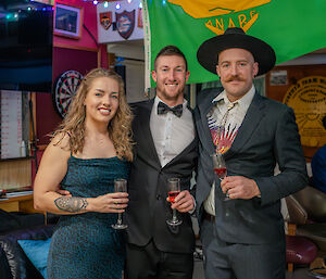 Three people in formal wear stand and smile to camera