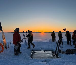 a view with expeditioners gathered around the sea ice cut out before 'swimming' begins