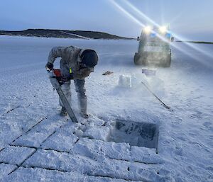 An expeditioner cutting through the sea ice to make a swimming pool for the Midwinter swim