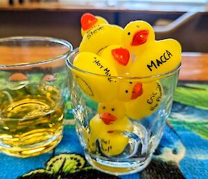 Two glasses, one full of liquor and the other, rubber ducks