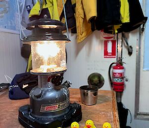 yellow plastic ducks sitting on a table near a lamp