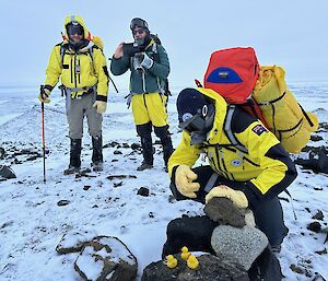 People standing on a snowy hillside with plastic ducks in the foreground