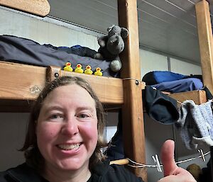 A smiling woman with ducks lined up on a bunk behind