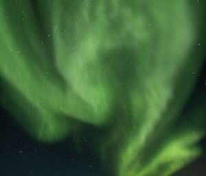A green aurora in the sky above buildings made of shipping containers.