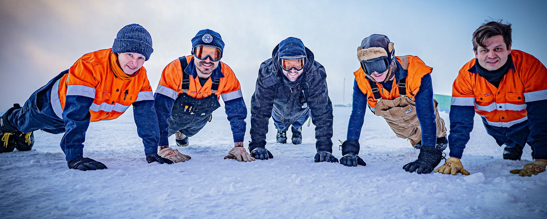 A group of five people doing a push up in Antarctica