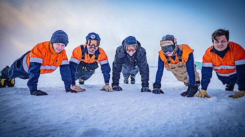 A group of five people doing a push up in Antarctica