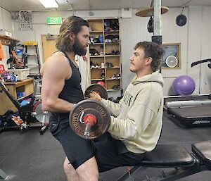 Two expeditioners in the Mawson gym helping each other to workout