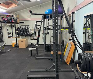 Before photo of station gymnasium, showing many weights racks and weights, it’s very cluttered