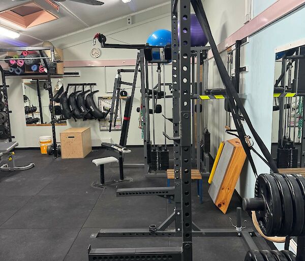 Before photo of station gymnasium, showing many weights racks and weights, it’s very cluttered