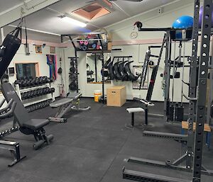 Before photo of station gymnasium, showing many weights racks and weights, it’s very cluttered