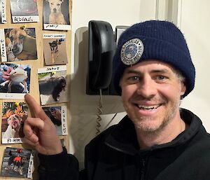 Close up of man, wearing AAD beanie, pointing at a photo of a Mexican walking fish