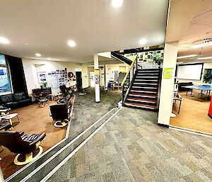 Stairs coming down into a large room with lounge chairs