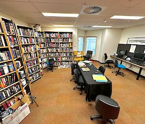 A room with lots of book shelves and books and computers