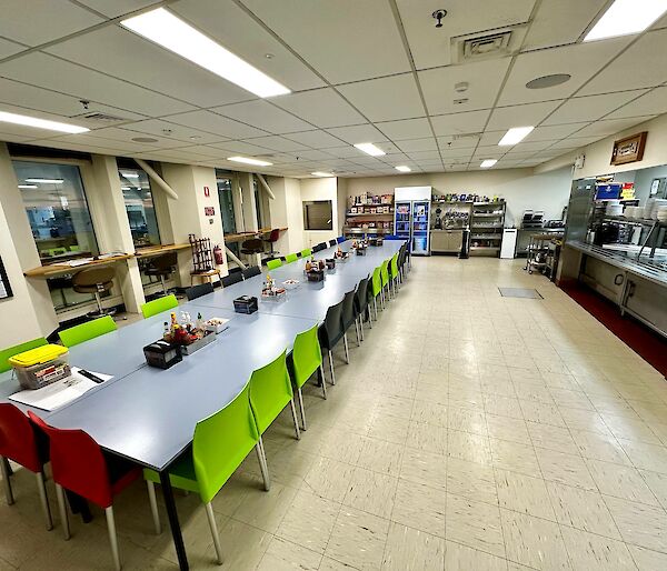 A large cafeteria with beige floor tiles and a long table
