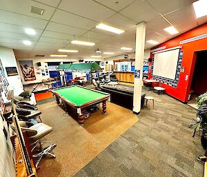 A large room with pool table and a red feature wall