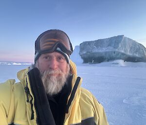 John standing in front of an iceberg that is distinctively a blue-green colour
