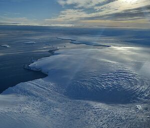 An aerial view of an icy island surrounded by sea