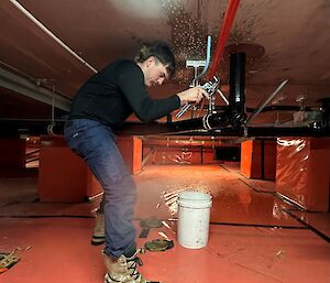 A man attends to a leak in the subfloor under the Red shed at Mawson station