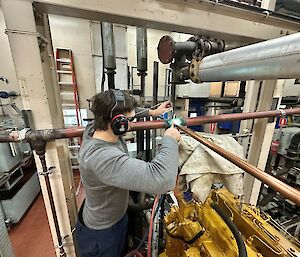 A person securing pipes in the Main Power House at Mawson station