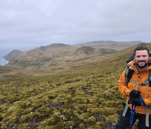 Man at top of large hill climb smiles to camera
