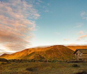 Beautiful golden light hits the south end of station where there is a small unused hut and then the mountains raise up behind