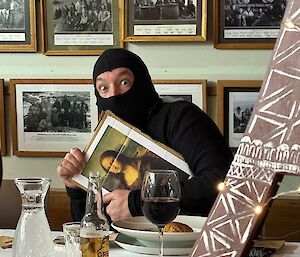 Man dressed as cat burglar carries a print out of the Mona Lisa painting