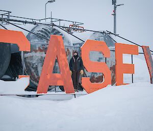 Alex stands next to the Casey sign. the sign is located in front of 6x 90,000 liter fuel holding tanks