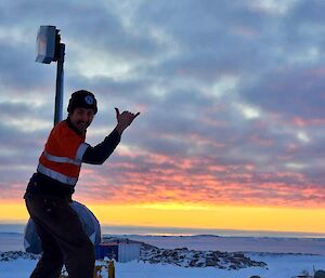 a cheekily smiling Alex throws a hand gesture 'shukka' as the sun sets on the Newcomb bay