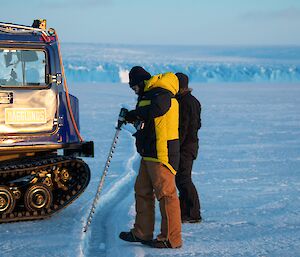 Testing a tide crack to see if the ice is safe to drive across near Mawson