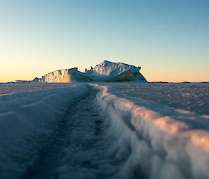 Ground view of a tide-crack showing the re-frozen sea ice and an iceberg in the distance where the crack terminates