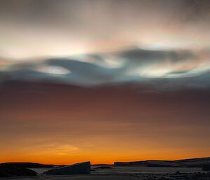 Iridescent clouds over icebergs and an orange sunset