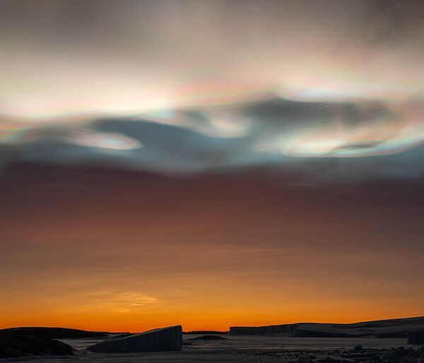 Iridescent clouds over icebergs and an orange sunset