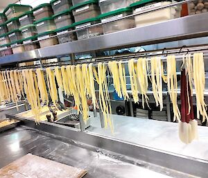 strings of pasta hanging over a rail