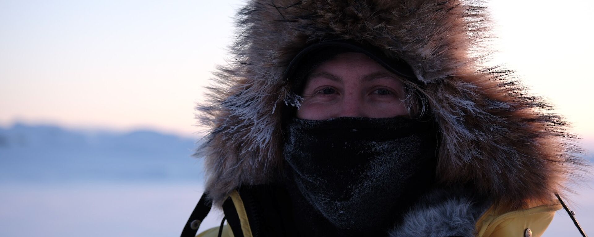 Expeditioner Peter Laughton wears cover mask and big wooly hat for a portrait taken on the sea ice during mid winter swim. A focused close shot with blurred backround