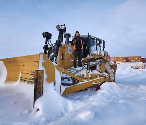 Mechanic Lewis stands atop a bull dozer after successfully re-instating a 'dozer' blade. Giving a thumbs up with a smile.