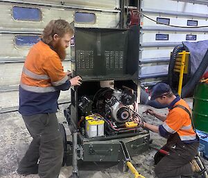 Two mechanics working hard at getting a Herman nelson (a portable diesel heater) up and running in the workshop