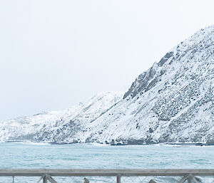 Front gate of station, reading "MACCA" in foreground with sea and snow covered mountain behind